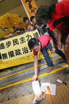 Raphael Wong and  “Long Hair” Leung Kwok-hung burn a copy of Beijing's white paper outside the court. Photo: David Wong