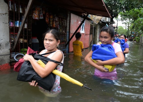 Residents affected by flooding due to heavy rains worsened by Tropical storm Trami wade through a flooded street in Calumpit, Bulacan province, north of Manila. Photo: AFP