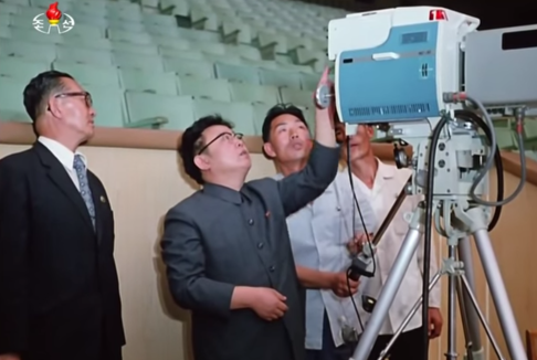 Kim Jong-il (2nd from left), fiddles with a camera inside a news studio, in this screengrab from an apparent KCTV online video.