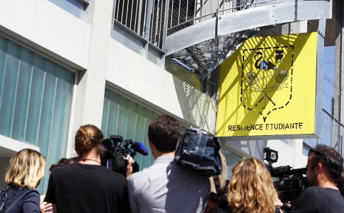 Journalists film the facade and the logo of the student residence where an IT student, suspected of planning a church attack in France. Photo: AFP