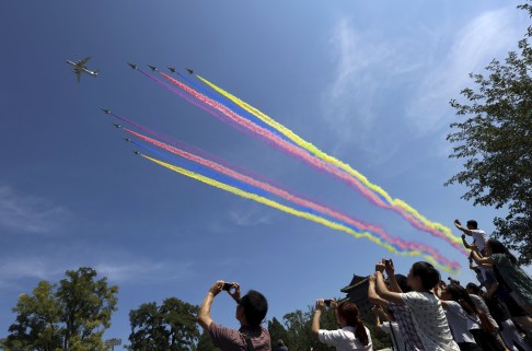 Spectators take photographs of aircraft against a bright blue sky during Thursday's military parade. Photo: Reuters