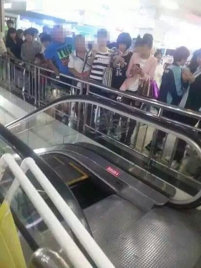 Chinese shoppers look at the missing flooring panel at the top of the escalator after Sunday's accident in Liaoning province. Photo: SCMP Pictures