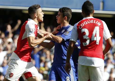 Chelsea's Oscar (centre) holds back Arsenal's Gabriel who had been show a red card for a second clash with Chelsea's Diego Costa at Stamford Bridge stadium. Chelsea won the game 2-0. Photo: AP