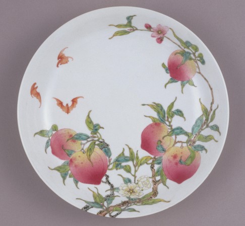 One of the famille-rose peach and bat decorated ceramic dishes on display.